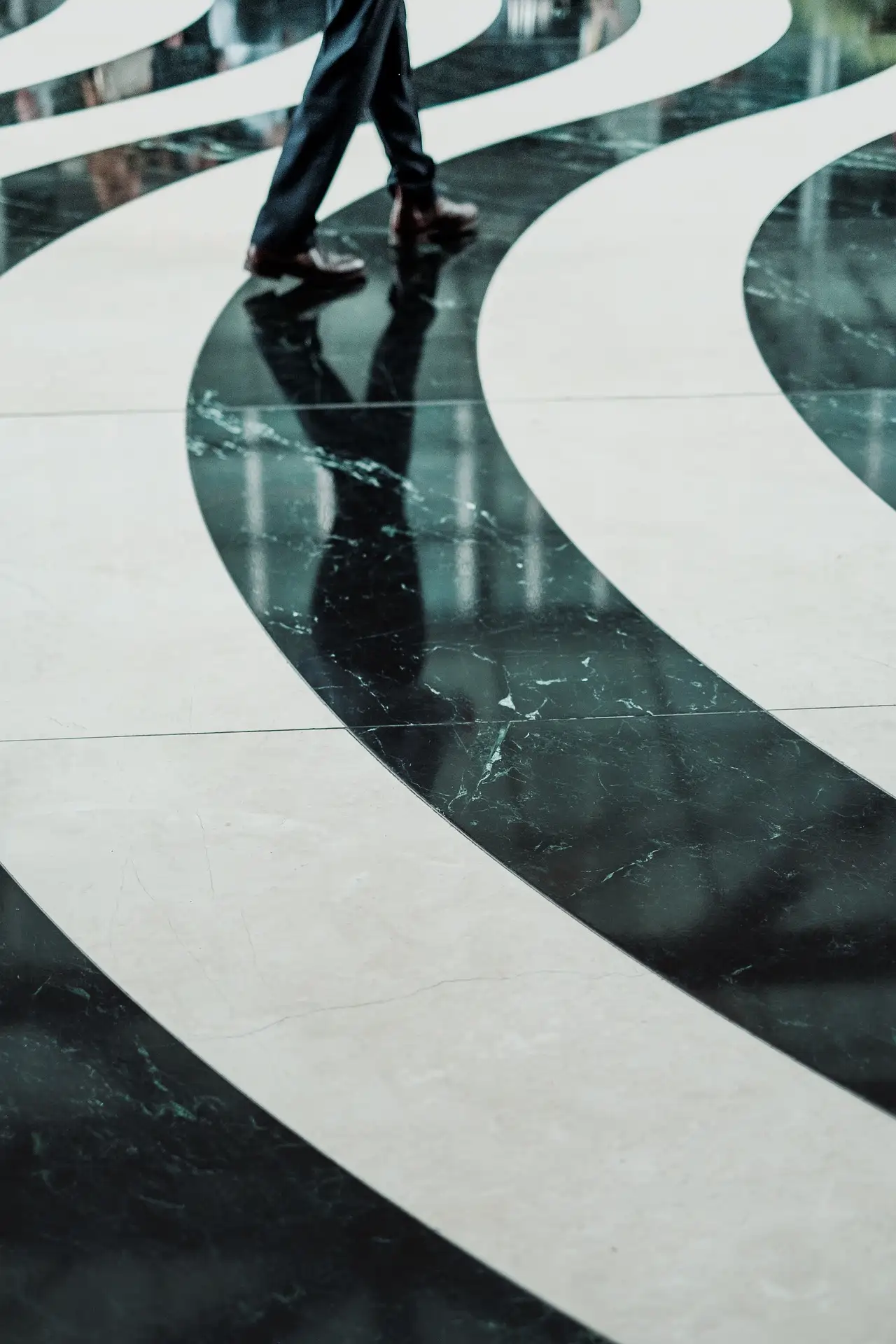 Dramatic black and white spiral marble tile floor design in a commercial lobby